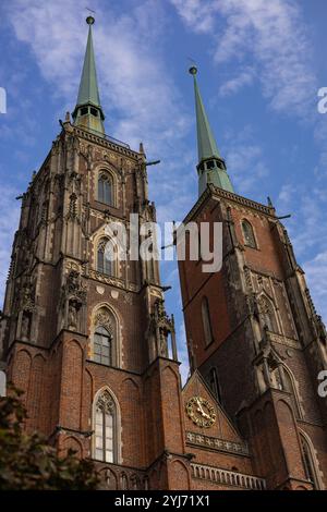 Gothic-style twin spires of Wroclaw Cathedral in Poland under blue sky, showcasing ornate architecture with pointed arches and intricate statues Stock Photo