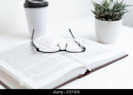 Open book with glasses resting on top, symbolizing reading, knowledge, study, and insight, representing concepts of learning, literature, wisdom, and Stock Photo