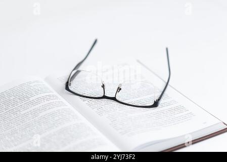 Glasses resting on open book with text, symbolizing reading, research, science, and law study, representing focused exploration of knowledge and acade Stock Photo