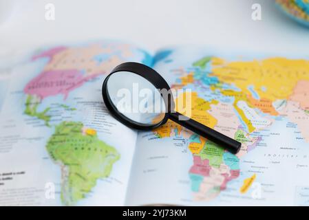 Magnifying glass on atlas map, symbolizing travel search, geography exploration, global discovery, and navigation planning Stock Photo