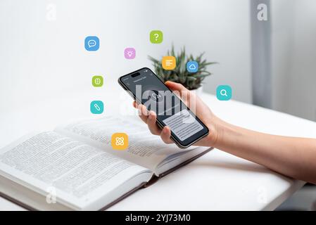 Hand holding smartphone above open book, using voice-to-text app for learning, representing audio search and text-to-speech technology, with floating Stock Photo