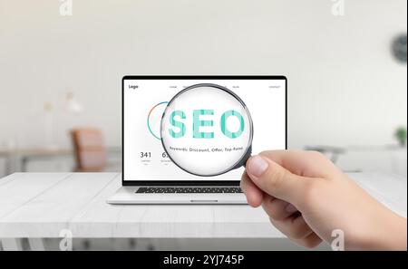 Magnifying glass highlighting SEO on laptop screen, symbolizing optimization and research for enhancing website performance and search engine visibili Stock Photo