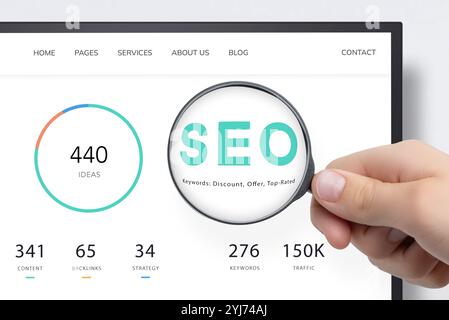Computer screen displaying SEO data with magnifying glass highlighting keywords, symbolizing research, keyword search, and analytics in digital market Stock Photo