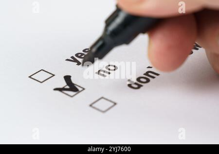 A close-up view of a hand using a black marker to select the answer on a checklist, confidently choosing yes over the other options in a clear decisio Stock Photo