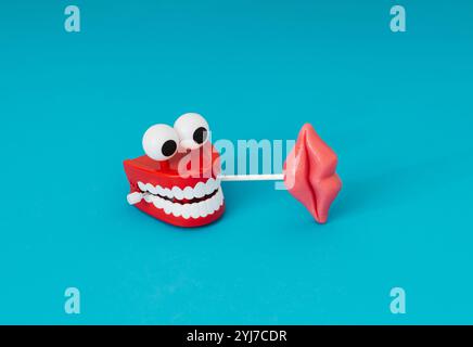 Valentines day composition with red lips lollipop in plastic toy teeth on light blue background. Creative aesthetic love concept. Stock Photo