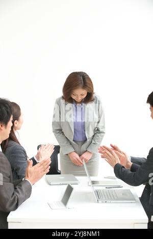 Businessperson applauding with a middle-aged office worker bowing Stock Photo