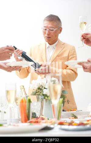 Man and home party guests looking at wine brands Stock Photo