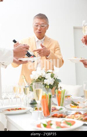 Man and home party guests looking at wine brands Stock Photo