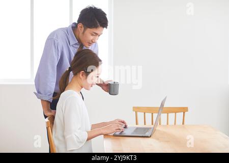 Couple watching computer in dining room Stock Photo - Alamy