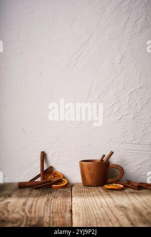 Wooden cup with cinnamon sticks and dried oranges on wooden top Stock Photo