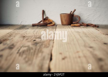 Wooden cup with cinnamon sticks and dried oranges on wooden top Stock Photo