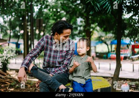 Southeast Asian father chatting with his child, capturing a moment of connection and care. Ideal for projects focused on family, parenting, or bonding Stock Photo