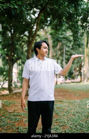 Southeast Asian man showing something with his right hand, highlighting an object or idea. Perfect for projects focused on demonstration, communicatio Stock Photo