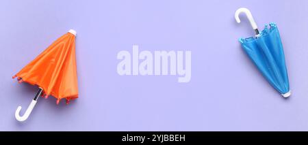 Stylish umbrellas on lilac background with space for text, top view Stock Photo