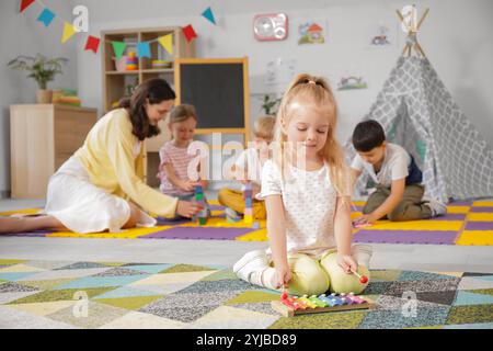 Cute little girl playing xylophone in kindergarten Stock Photo