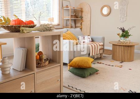Sofa, cushions on floor and decor on sideboard in autumn interior of living room Stock Photo