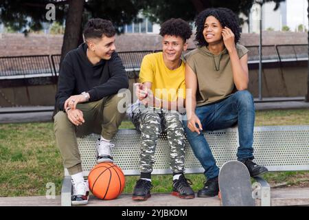 teen male friends smiling happy sitting on bench Stock Photo
