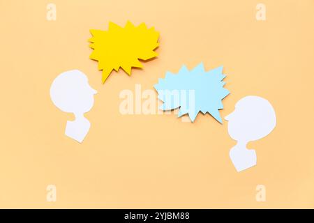 Paper human heads with blank speech bubbles on color background Stock Photo