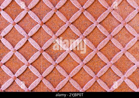 Wall decoration with marble carving. Part of decorative wall with ornamental symmetrical arabesque motifs carved on pink brown marble slab. Stock Photo