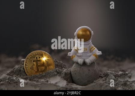 Manipulated currency valuations. Toy Astronaut, Gold Bitcoin on the Moon. Bitcoin Mining in Space concept Stock Photo