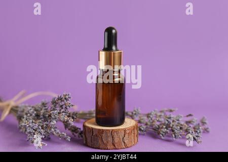 Cosmetic brown glass bottle for essential oil Lavender Mockup. Lavender Cosmetics Podium on violet background Stock Photo