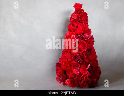 unusual christmas tree made by red paper roses isolated on gray Stock Photo