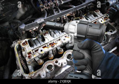 A mechanic use a cordless impact wrench to repairing a car engine , Car repair concept Stock Photo