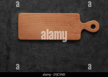 Empty brown Wood Cutting Board on Black Cement background. Top view, copy space. Square Mock up Stock Photo