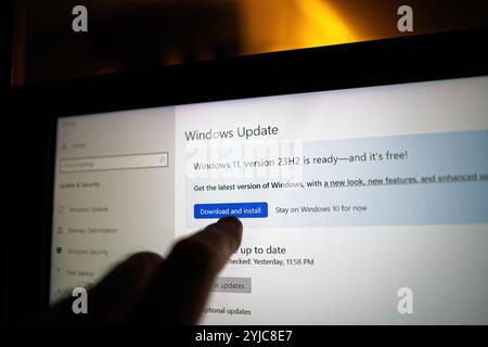 Paris, France - Sep 10, 2024: Finger pointing to the Windows Update screen on a laptop, highlighting the Download and install button for Windows 11 version 23H2, ready for upgrade. Stock Photo