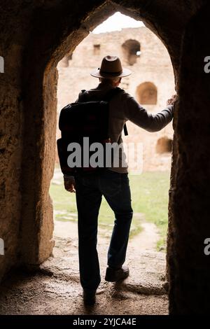 Retired male tourist gazes from arch within the brick walls of an ancient fortress standing near space for text. travel and tourism Stock Photo