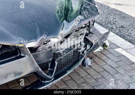 Black car with severe front-end damage after a collision. The photo highlights the significant impact and damage to the vehicle, making it a powerful Stock Photo