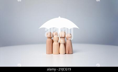 Protect and care for your family, umbrella above a family cover and shelter wooden people, security, protection, Finance or insurance concept, People Stock Photo