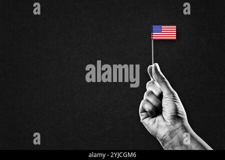 Hand in Black and White Holding an American Flag, Black Textured Background with Copy Space Stock Photo