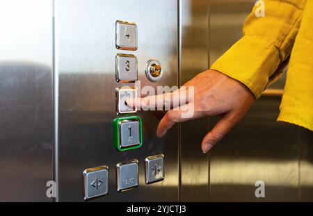 Woman pressing button inside elevator. Stock Photo