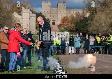 Windsor, UK. 14th November, 2024. Ray Butler of Shellscape Pyrotechnics supervises a member of the public in firing a small cannon during a 21-gun salute on the Long Walk in front of Windsor Castle to mark King Charles III's 76th birthday. An invitation was issued to local children to help celebrate the traditional gun salute for King Charles III. Credit: Mark Kerrison/Alamy Live News Stock Photo