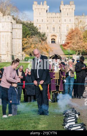 Windsor, UK. 14th November, 2024. Ray Butler of Shellscape Pyrotechnics supervises a mother and young child in firing a small cannon during a 21-gun salute on the Long Walk in front of Windsor Castle to mark King Charles III's 76th birthday. An invitation was issued to local children to help celebrate the traditional gun salute for King Charles III. Credit: Mark Kerrison/Alamy Live News Stock Photo