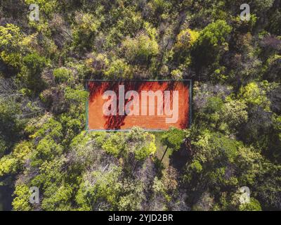 Tennis court in the forest from aerial top view. Stock Photo