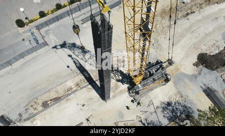 Aerial view of a construction site with a crane and workers handling rebar structures Stock Photo