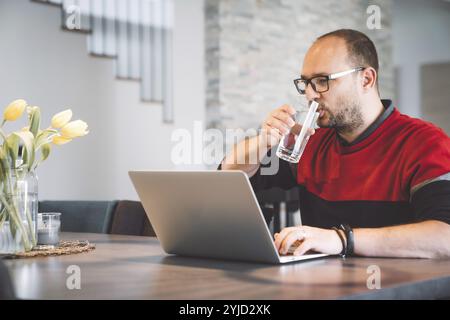 Adult caucasian man working from home a couple days a week. Adult person working from home, from different rooms in the house, in the kitchen, dining Stock Photo