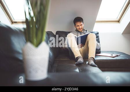 Smiling caucasian man freelancer using laptop studying online working from home, happy casual millennial guy typing on laptop surfing internet looking Stock Photo