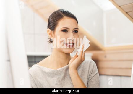 Beautiful young woman cleaning her face, removing make up with a cotton pad and micellar water. Skin care and beauty. Young beautiful woman cleaning h Stock Photo