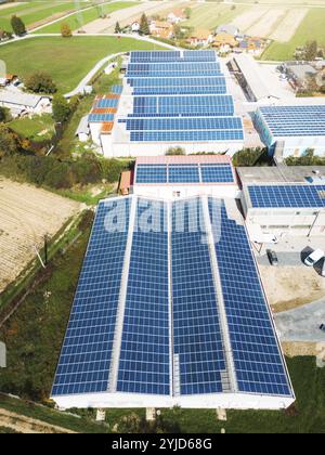 Solar panels installed on a roof of a large industrial building or a warehouse. Industrial building in the country side of Slovenia with residential h Stock Photo