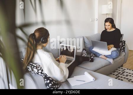 Two young caucasian woman students studying at home in their apartment. Learning with friends at the campus. Sorority concept. Stock Photo