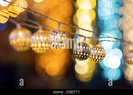 Metal string LED lights hanging outdoors for decorations during Christmas celebrations at night in city Stock Photo