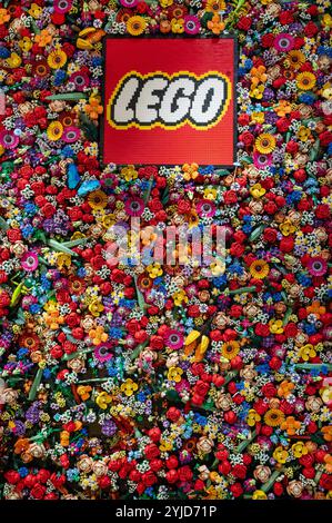 Lego logo is displayed on a wall covered with colorful Lego flowers inside the lego store in Milan Stock Photo
