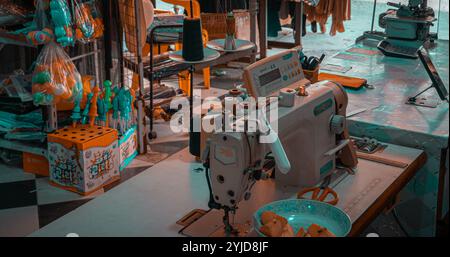 Sewing workspace filled with vibrant thread spools, sewing machines, and various crafting materials, offering a glimpse into the bustling and creative Stock Photo
