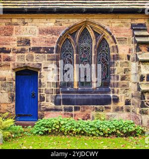 The back door of St Michael and All Angels church, Croston, Lancashire, adjacent to the stained glass window viewed from outside Stock Photo