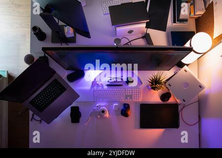 creative studio equipment desk from above laptop graphic tablet camera photo editor neon light Stock Photo