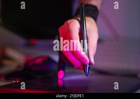 hand holding digital stylus on graphic tablet studio equipment creative tools neon light Stock Photo