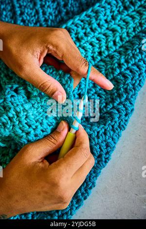 African American Hands Crocheting with Blue Yarn Close-Up Motion Stock Photo
